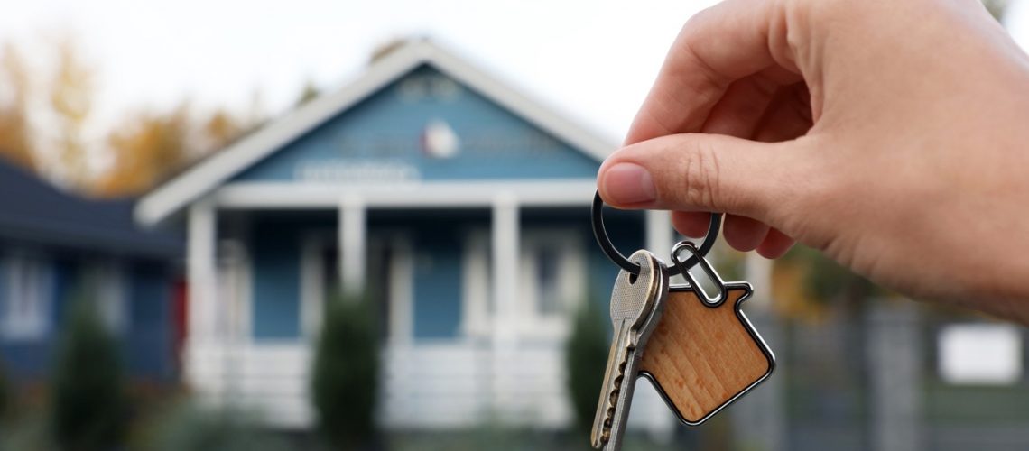 Woman holding house keys outdoors, closeup with space for text. Real estate agent